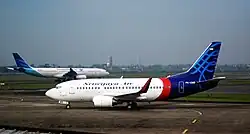 A Sriwijaya Air Boeing 737-500 at Soekarno Hatta Airport with a Garuda Indonesia Airbus A330-300 in the background.