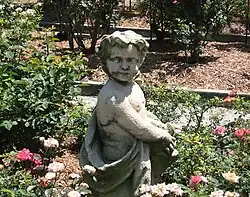 Statue in a rose garden with plantings in background