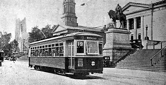 A streetcar passing a Neoclassical courthouse on an urban street
