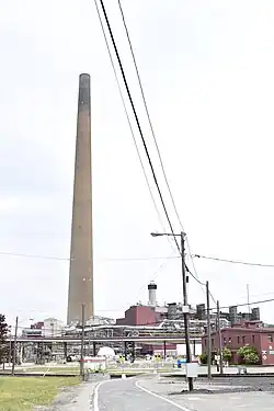 A tall smokestack rising from a refinery on a sunny day