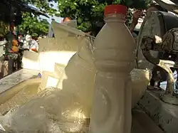 A bottle of suero costeño in foreground and costeño cheese in background at a market stand in Barranquilla.