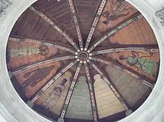 "Circular coffered ceiling divided into twelve sections radiating from the center. Nine sections have Greek figures painted on wood insets. Three are blank and have no figures.