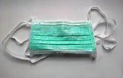 A surgical face mask, meant for single use.[66] It is a type of the face masks often used to prevent the spread of Coronavirus. They are used in countries with coronavirus disease (COVID-19) outbreaks and are worn in hospitals as well as in public. They are not designed to protect the wearer from inhaling airborne bacteria or virus particles and are less effective than respirators, such as N95 or FFP masks.[69]