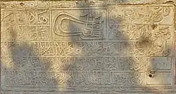 photo of a stone slab with Arabic lettering, and a Sultan's tughra in the upper middle