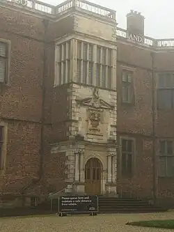 Photograph of entrance porch of Temple Newsam House, Leeds, showing at top the word 'FATHER', below a mullioned window, below a raised portico with coat of arms above a doorway flanked by two Ionic columns on each side.