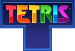 The word "Tetris", each letter a different color, engraved on a blue, T-shaped tetromino.