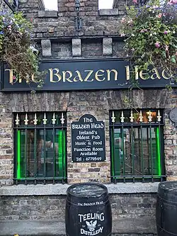 Portrait photograph of The Brazen Head exterior with sign and a plaque reading "The Brazen Head, Ireland's Oldest Pub, Music & Food, Function Room"