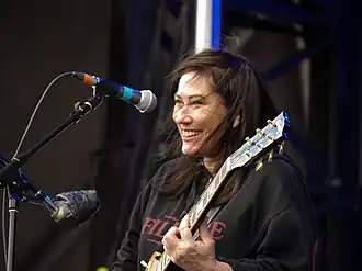 Kim Deal playing guitar onstage in 2018