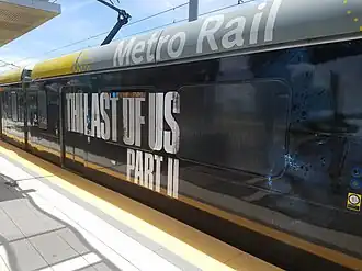 A train with an advertisement for the game: the large block text says "The Last of Us Part II", with a dark picture of Ellie's face.