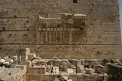 slightly curved blocks form the spring of an arch in the middle of a wall of otherwise flat-faced stones