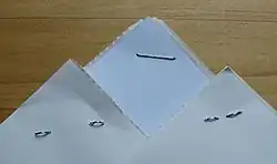 Staples in use, showing the front side (center), and two examples of the back side: the legs bent outward on the left, and inward on the right