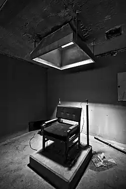 Electric chair on a low pedestal, under a light