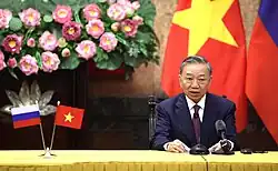 General Secretary Tô Lâm with lotus decorations behind him.
