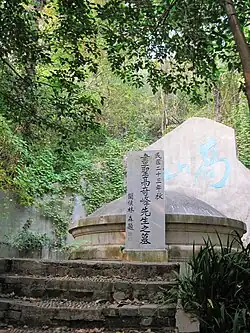 A tomb with a round top, located behind a stele on which a Chinese-language inscription is written
