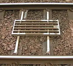 An image of a TPWS OSS loop antenna, a silver coloured rectangular object positioned along the sleepers, between the two running rails of the track.