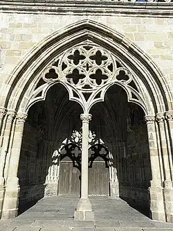 "Le porche du peuple" on the south side of the cathedral. The porch leads to a double-doored entrance to the cathedral and the side walls are decorated with statues of the Evangelists and others. Note the elaborate rosace at the top of the porch's supporting colonnette.