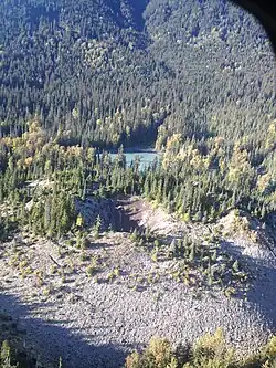 A sparsely tree-covered volcanic cone with a bowl-shaped crater on the top