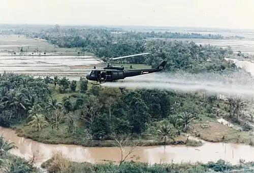 A US helicopter spraying Agent Orange on a jungle during the Vietnam War,