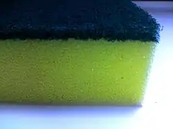 A close-up of one corner of a urethane abrasive sponge with a top layer used for more intense dish scrubbing