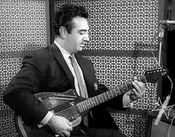 Black-and-white photo of guitarist wearing a suit while playing in the studio
