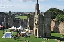 A crowd of people gathered near a tent within the castle