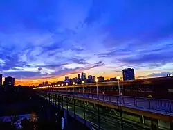 A view of the bridge at night. The bridge is lit by lampposts, and the Minneapolis skyline is visible in the background.