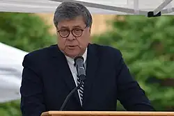 William Barr speaking at a podium