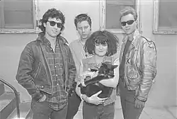 The band standing, with Exene holding a cat