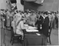 Lieutenant General Richard K. Sutherland, aboard USS Missouri, corrects a signatory error in the Japanese Instrument of Surrender. US Colonel Sidney Mashbir and Japanese Foreign Minister Katsuo Okazaki look on.